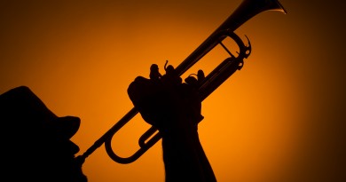 backlight musician playing trumpet on orange background