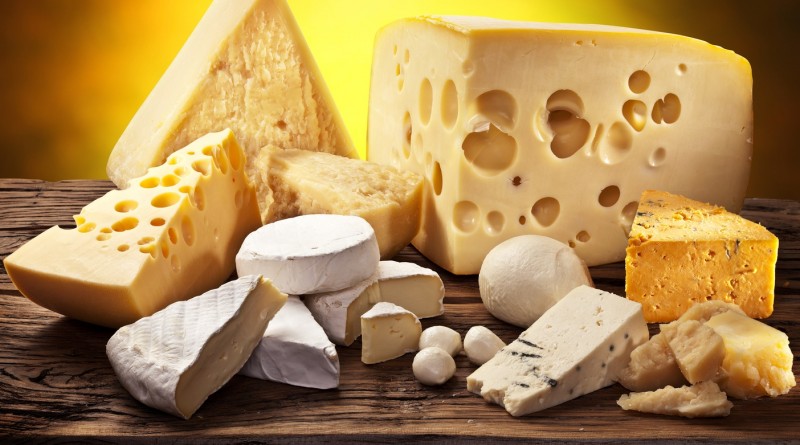 Different types of cheese over old wooden table.