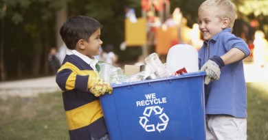 Two boys carrying recycling container