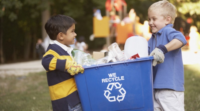 Two boys carrying recycling container